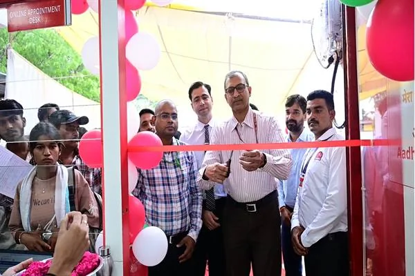 गुब्बारों से सजे आधार सेवा केंद्र के प्रवेश द्वार पर लाल फीता काटते अधिकारी और आसपास खड़े लोग